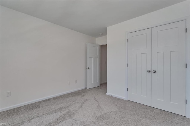 unfurnished bedroom featuring light colored carpet and a closet