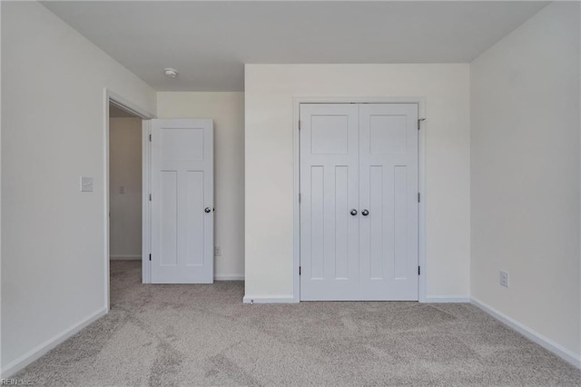 unfurnished bedroom featuring a closet and light carpet