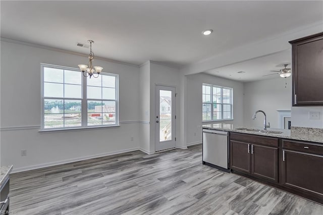 kitchen with dishwasher, sink, light stone counters, and dark brown cabinetry