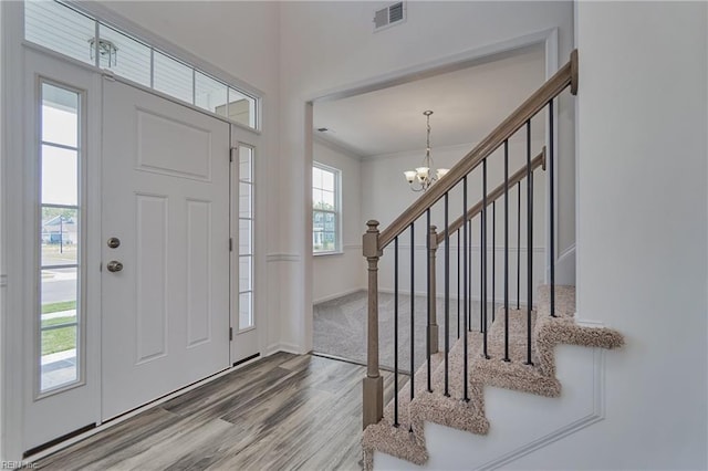 foyer with an inviting chandelier, hardwood / wood-style floors, and ornamental molding