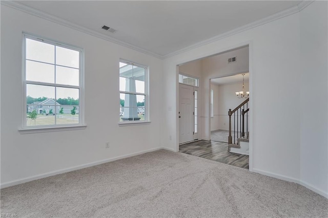 entrance foyer featuring ornamental molding, carpet, and a chandelier