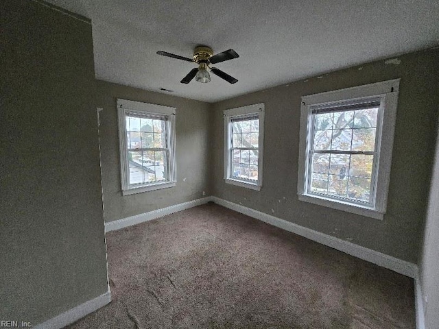 empty room with ceiling fan, carpet, a healthy amount of sunlight, and a textured ceiling