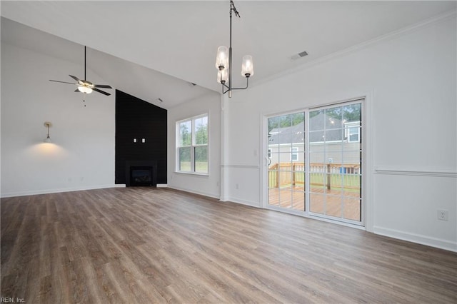 unfurnished living room featuring crown molding, hardwood / wood-style flooring, a fireplace, ceiling fan with notable chandelier, and vaulted ceiling