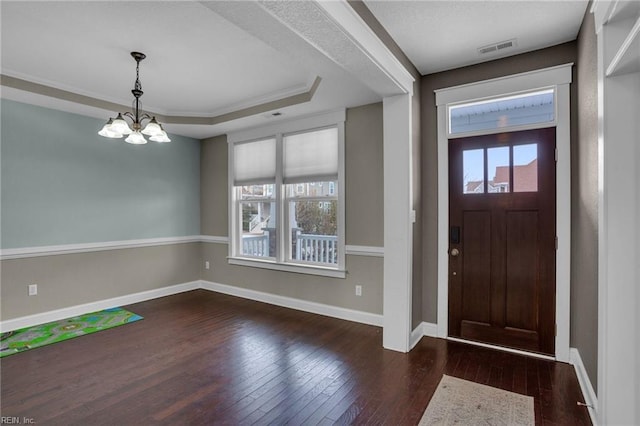 foyer entrance featuring ornamental molding, dark hardwood / wood-style floors, a notable chandelier, and a tray ceiling