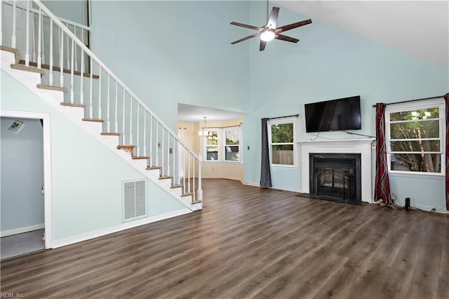 unfurnished living room featuring dark wood-type flooring, ceiling fan, and a high ceiling