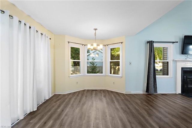 unfurnished dining area with dark wood-type flooring, a healthy amount of sunlight, and a chandelier