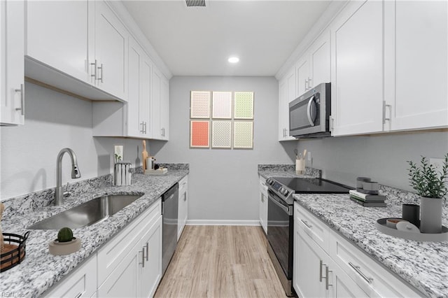 kitchen featuring sink, light wood-type flooring, white cabinets, and appliances with stainless steel finishes