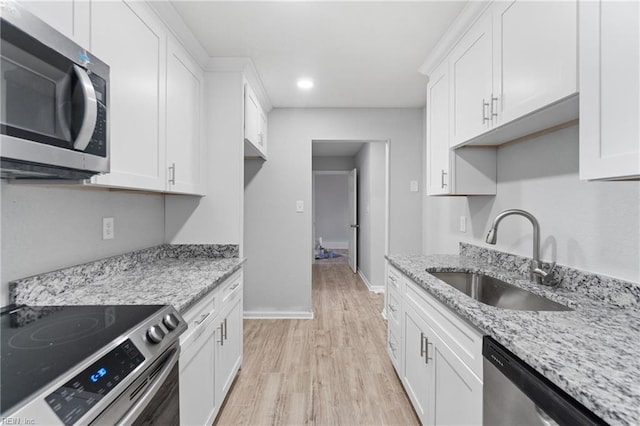 kitchen featuring stainless steel appliances, light stone countertops, sink, and white cabinets