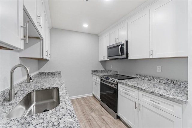 kitchen featuring white cabinetry, appliances with stainless steel finishes, sink, and light stone counters