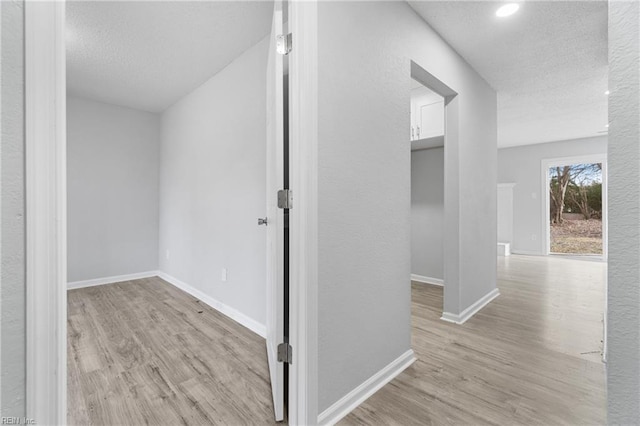 hall featuring light hardwood / wood-style flooring and a textured ceiling