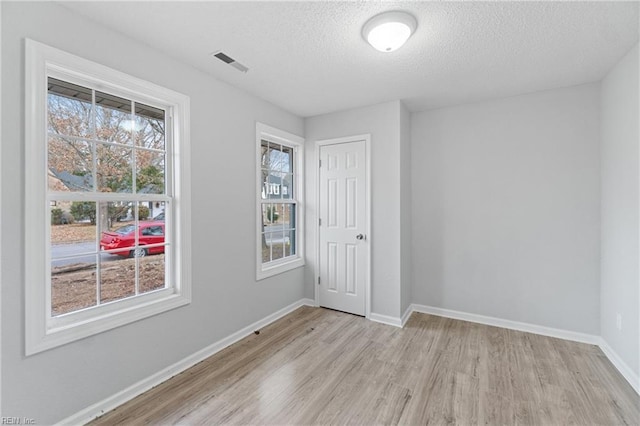 unfurnished room featuring light hardwood / wood-style flooring and a textured ceiling