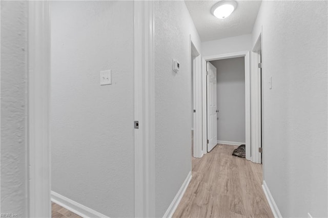 hallway featuring a textured ceiling and light wood-type flooring