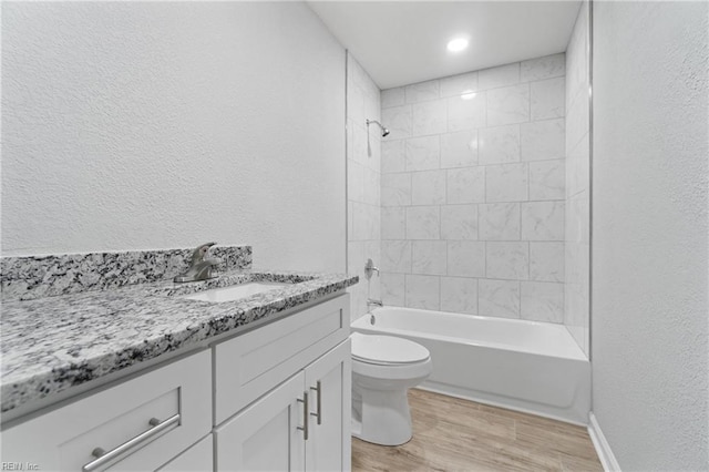 full bathroom featuring hardwood / wood-style flooring, vanity, toilet, and tiled shower / bath combo