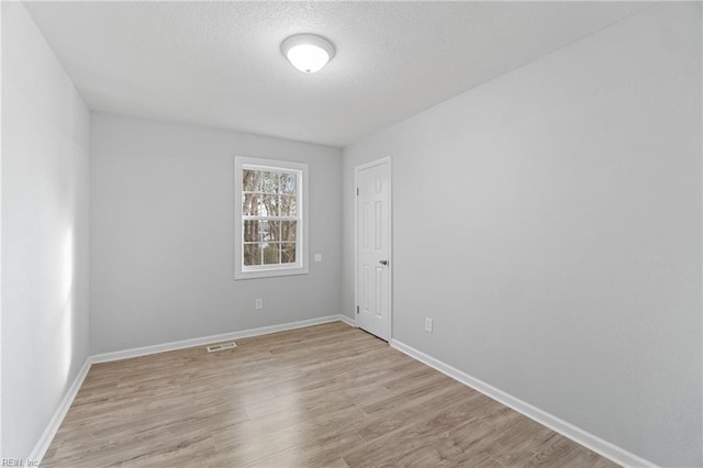 spare room featuring a textured ceiling and light hardwood / wood-style flooring