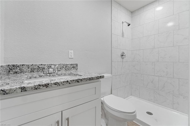 bathroom featuring vanity, tiled shower, and toilet