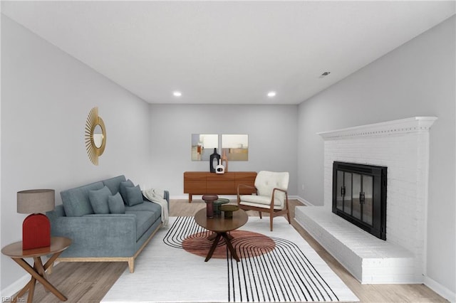 living room with a fireplace and light wood-type flooring