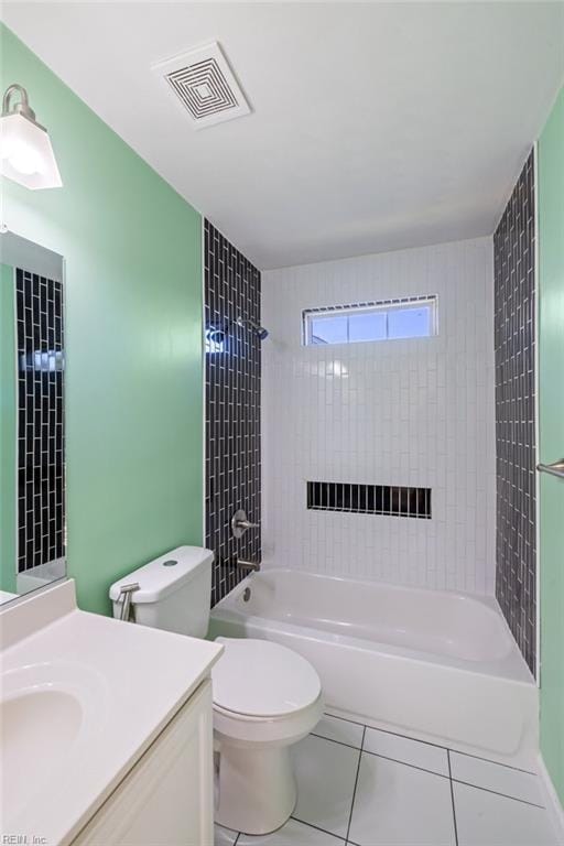 full bathroom featuring tile patterned flooring, vanity, tiled shower / bath combo, and toilet