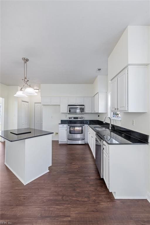 kitchen featuring sink, white cabinetry, dark hardwood / wood-style flooring, pendant lighting, and stainless steel appliances