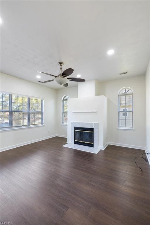 unfurnished living room with ceiling fan, plenty of natural light, dark wood-type flooring, and a fireplace