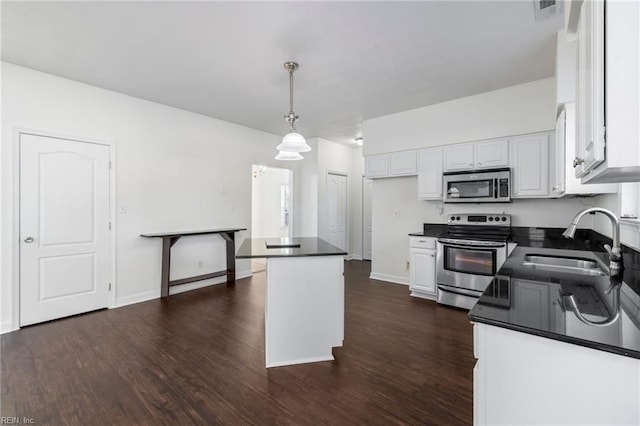 kitchen with hanging light fixtures, appliances with stainless steel finishes, sink, and white cabinets