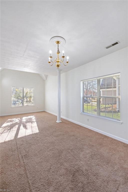 spare room featuring lofted ceiling, carpet floors, and a chandelier