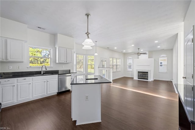 kitchen featuring sink, dishwasher, white cabinets, a kitchen island, and decorative light fixtures