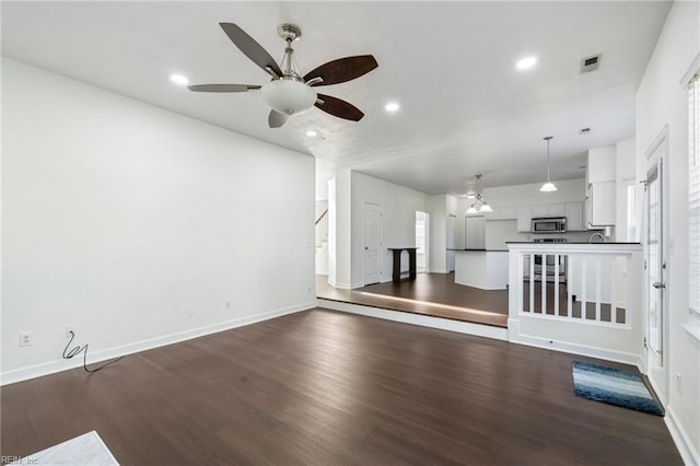 unfurnished living room featuring dark wood-type flooring, ceiling fan, and sink