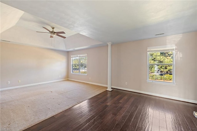 spare room featuring decorative columns, dark hardwood / wood-style floors, ceiling fan, and a tray ceiling