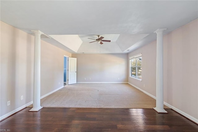 empty room with ornate columns, a raised ceiling, hardwood / wood-style flooring, and ceiling fan