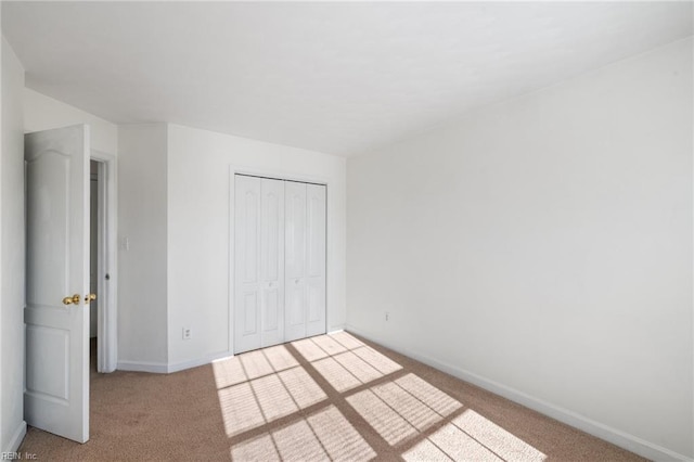 unfurnished bedroom featuring light colored carpet and a closet