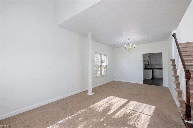 unfurnished living room featuring decorative columns, carpet flooring, and a notable chandelier