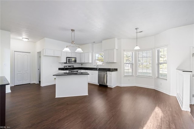 kitchen featuring stainless steel appliances, dark hardwood / wood-style floors, hanging light fixtures, and white cabinets