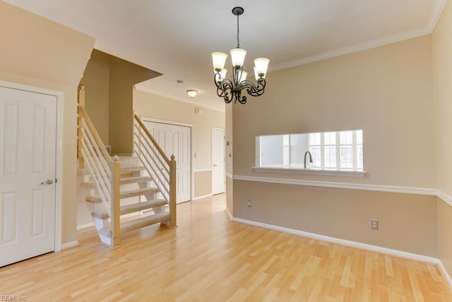 spare room with crown molding, hardwood / wood-style floors, and an inviting chandelier