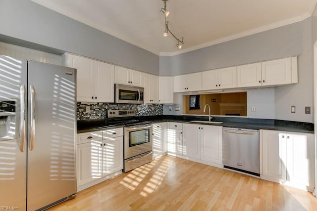 kitchen featuring sink, white cabinetry, tasteful backsplash, light hardwood / wood-style flooring, and appliances with stainless steel finishes