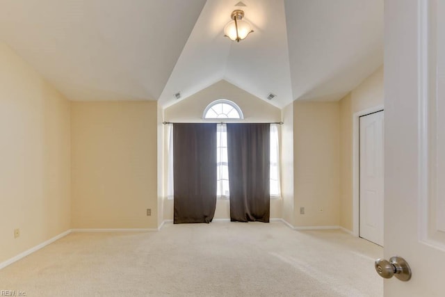 unfurnished room featuring vaulted ceiling and light carpet