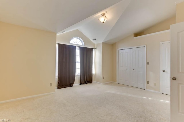 unfurnished bedroom with lofted ceiling, light carpet, and a closet