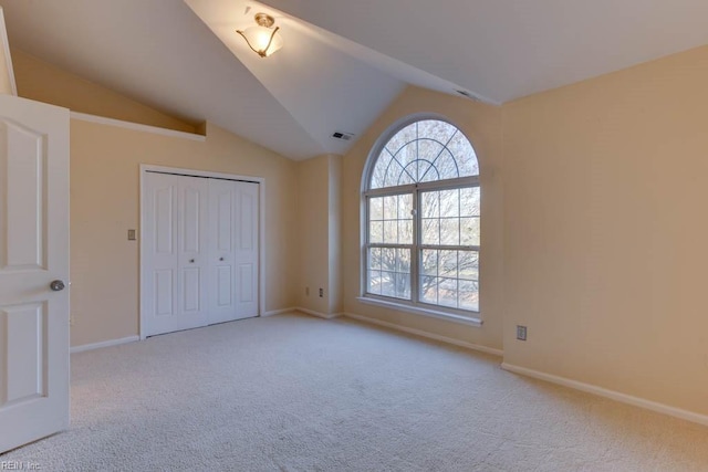 unfurnished bedroom featuring light carpet, vaulted ceiling, and a closet