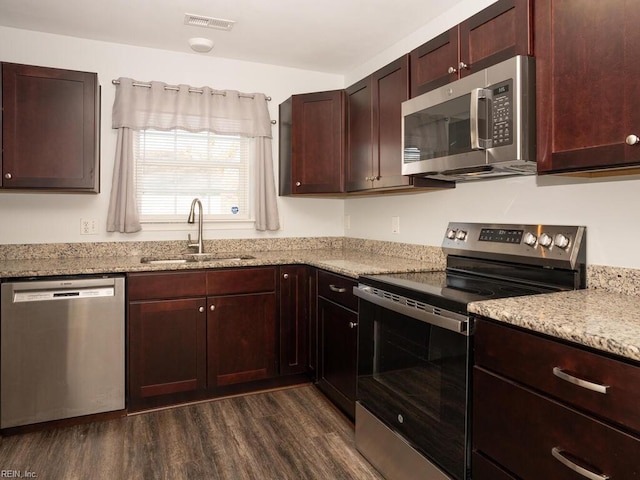 kitchen featuring dark wood-type flooring, stainless steel appliances, light stone countertops, and sink