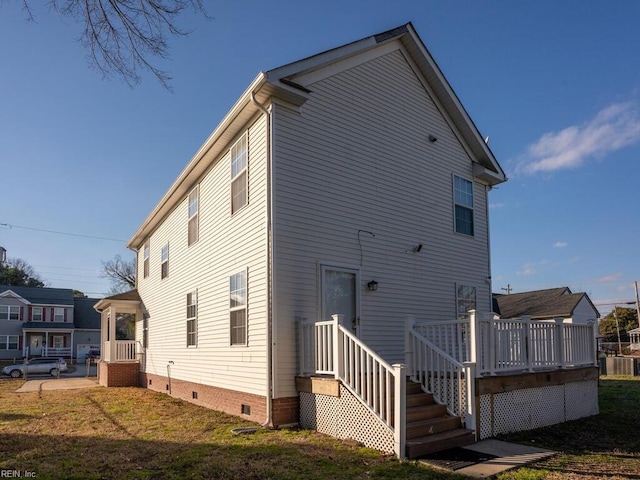 rear view of house featuring a lawn and a deck