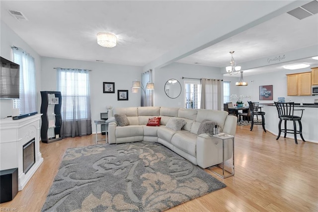 living room with a notable chandelier, plenty of natural light, and light hardwood / wood-style floors