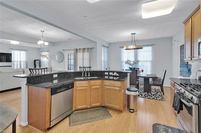 kitchen featuring sink, decorative light fixtures, stainless steel appliances, and dark stone counters