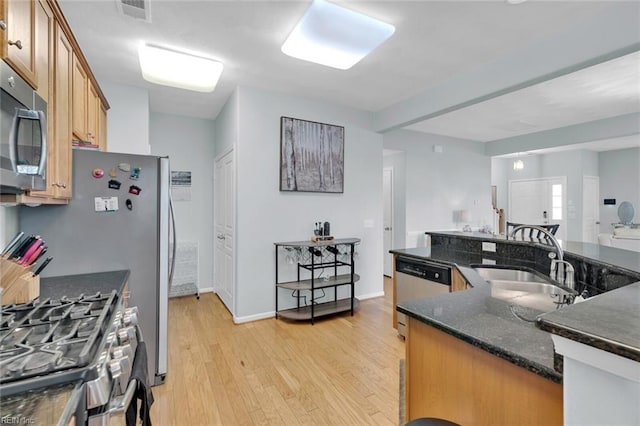 kitchen with dark stone countertops, sink, light hardwood / wood-style flooring, and stainless steel appliances