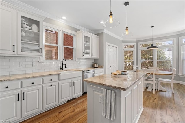 kitchen featuring a kitchen island, decorative light fixtures, white cabinetry, sink, and stainless steel dishwasher