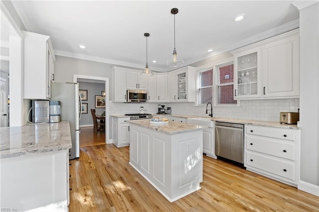 kitchen with a kitchen island, appliances with stainless steel finishes, decorative light fixtures, white cabinetry, and light stone countertops