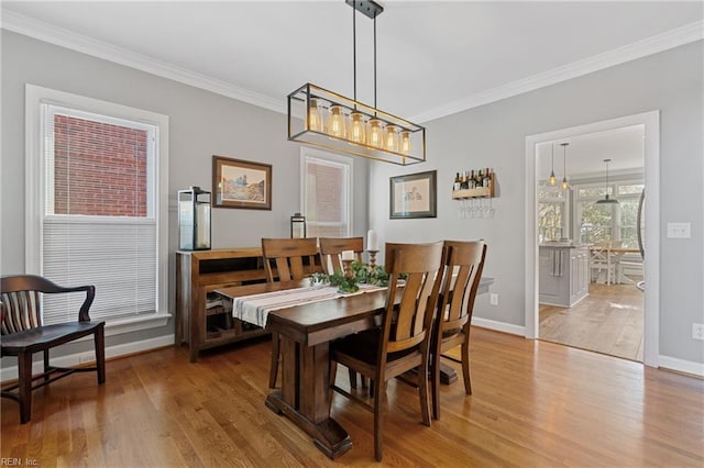 dining area with ornamental molding and light hardwood / wood-style flooring