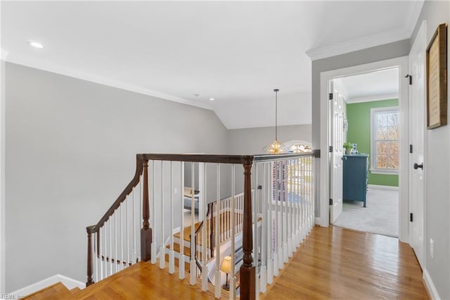 hall featuring vaulted ceiling, ornamental molding, plenty of natural light, and light wood-type flooring