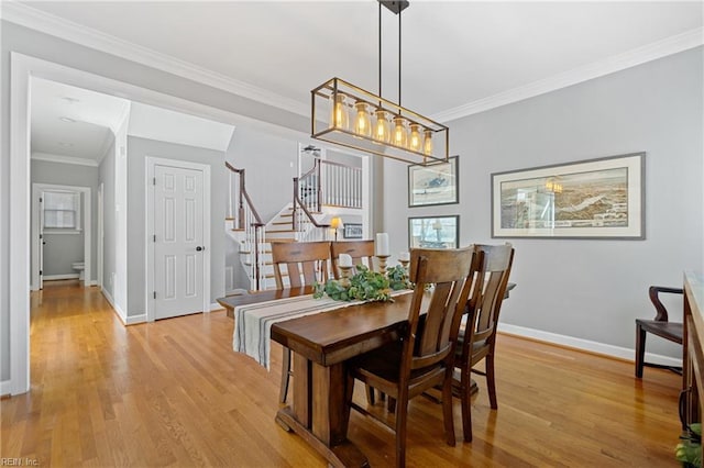 dining space with light hardwood / wood-style flooring and ornamental molding