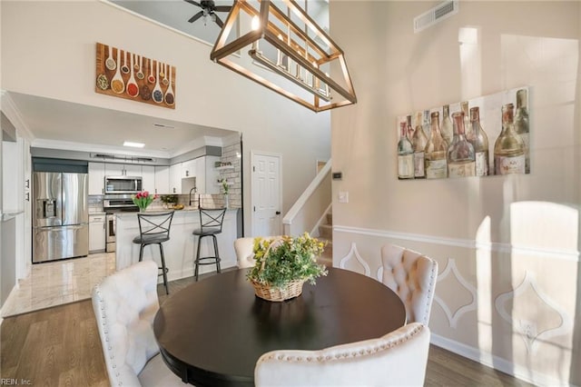 dining room featuring sink, dark wood-type flooring, ornamental molding, and ceiling fan