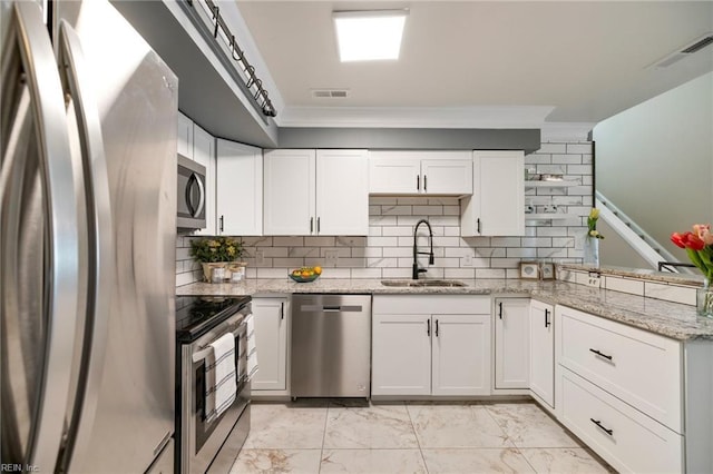 kitchen featuring white cabinetry, appliances with stainless steel finishes, light stone countertops, and sink