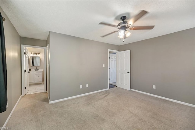 unfurnished bedroom featuring light colored carpet, ceiling fan, and ensuite bath